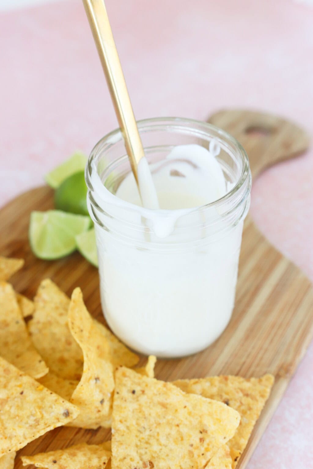 4 Ingredient Greek Yogurt Lime Crema in a white bowl on a butcher block with chips and limes on the side