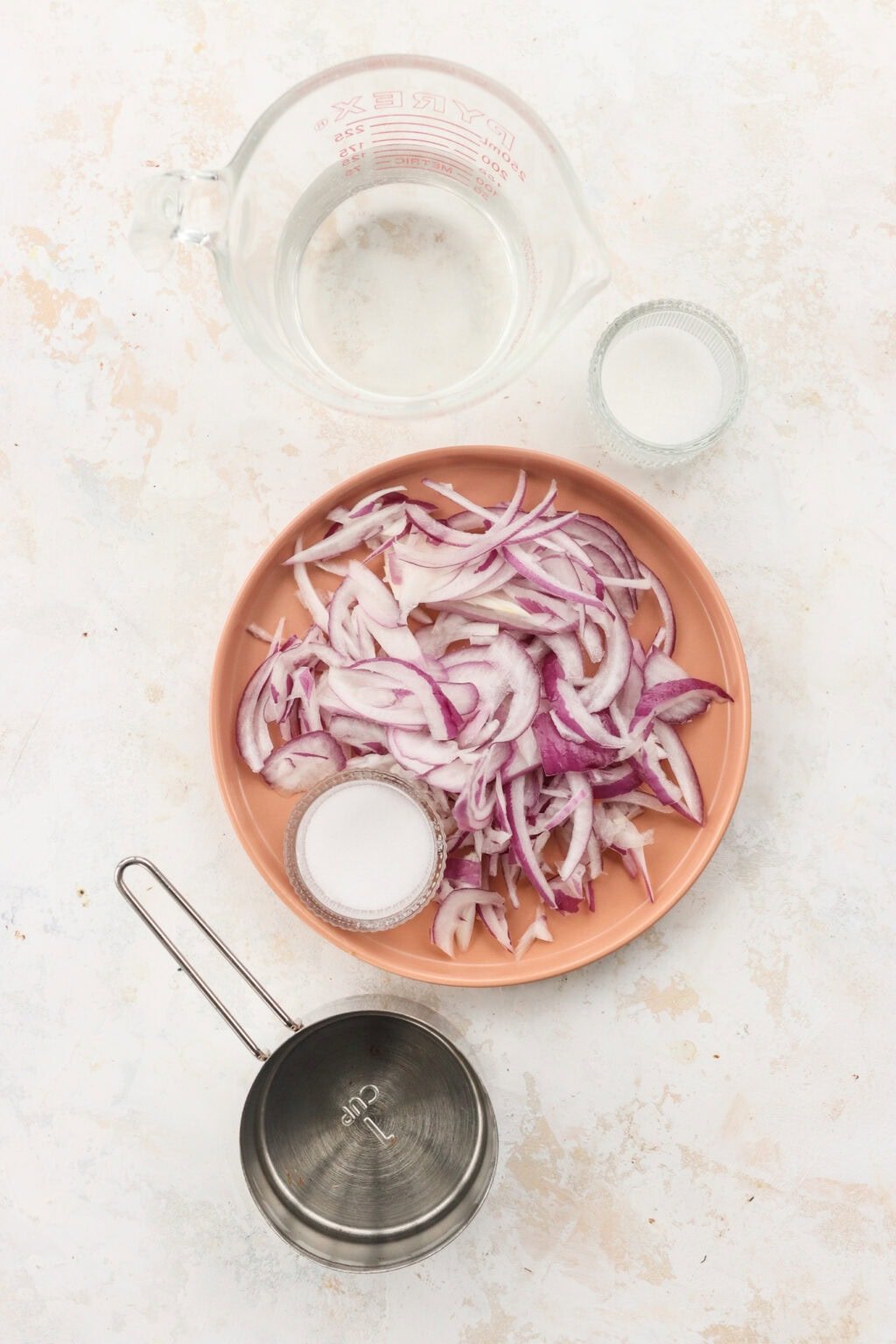 Ingredients for quick pickled red onions, including red onions, salt, sugar, vinegar, and hot water