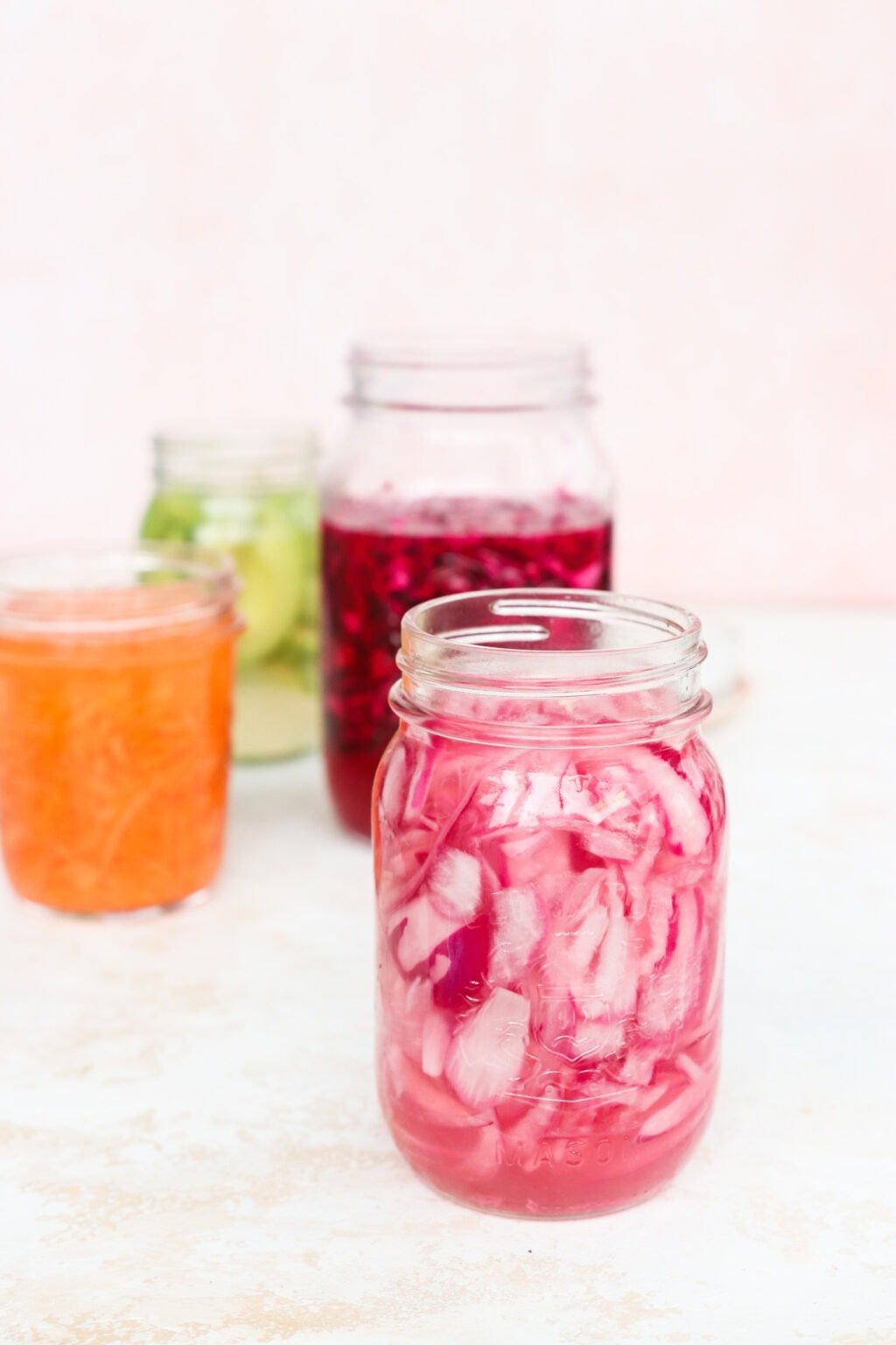 Quick pickled shredded carrots, red cabbage, avocados, and red onion in glass jars