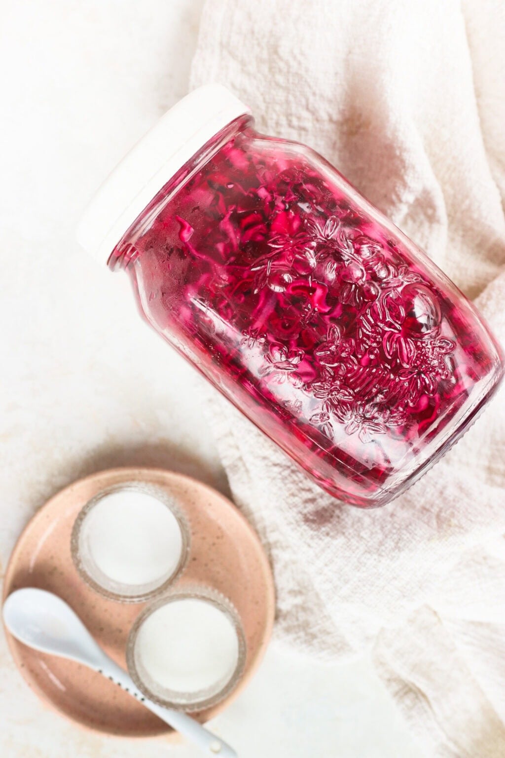 Quick pickled red cabbage in a glass jar with a pink plate beside it