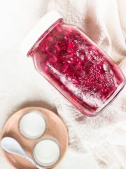 Quick pickled red cabbage in a glass jar with a pink plate beside it