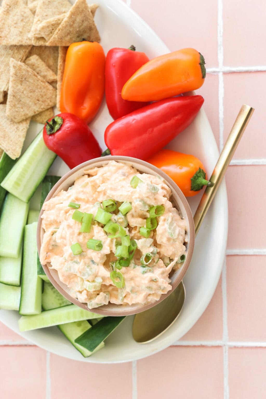 Quick Buffalo Chicken Salad with Greek Yogurt in a glass bowl on a white serving tray with celery, peppers, and crackers on the side