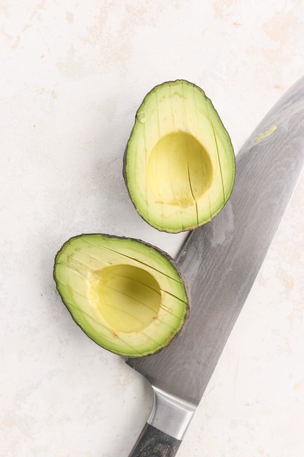 An avocado cut in half with a knife beside it