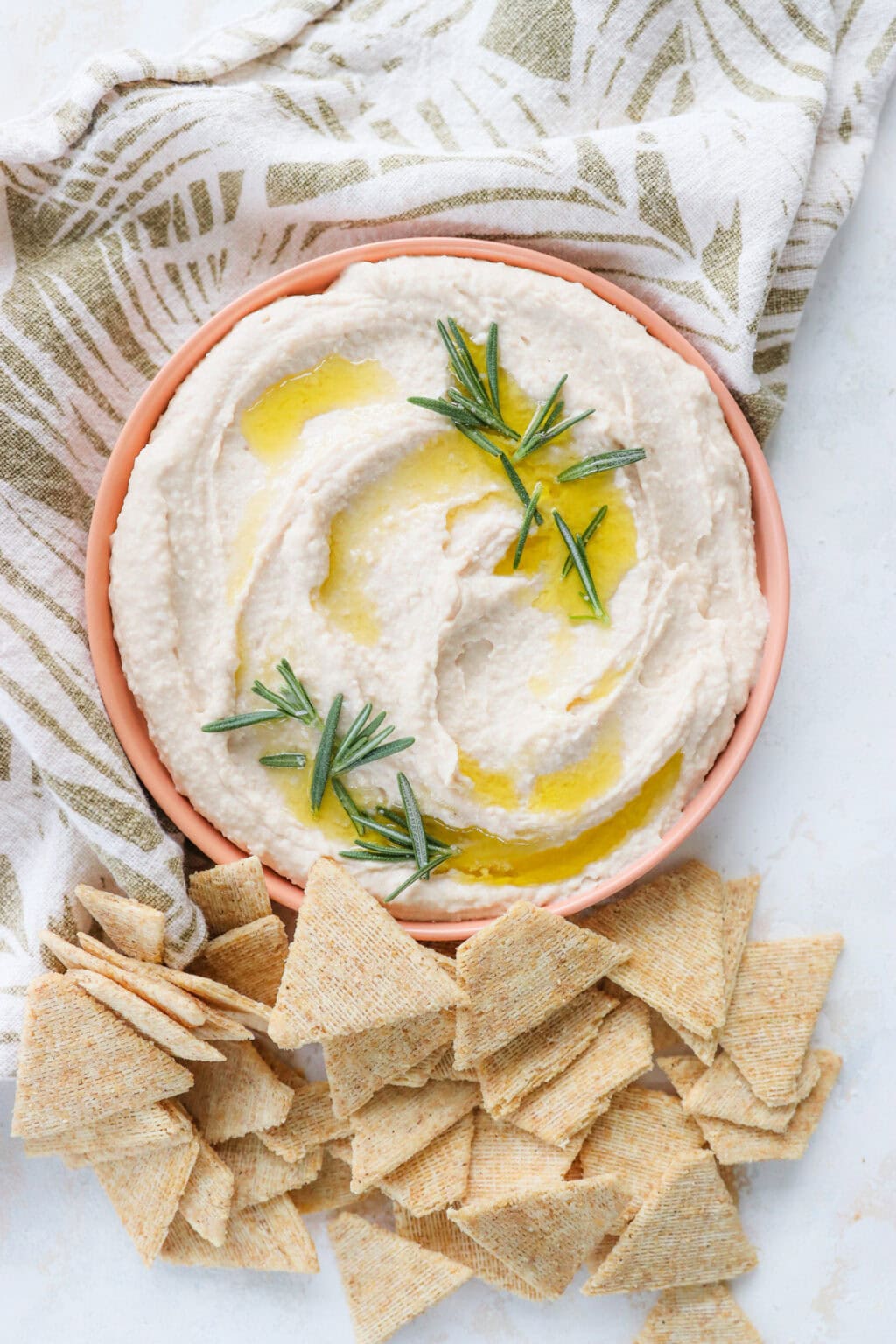 Super Creamy Vegan White Bean Dip with Cashews in a pink bowl with crackers on the side