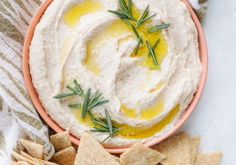 Super Creamy Vegan White Bean Dip with Cashews in a pink bowl with crackers on the side