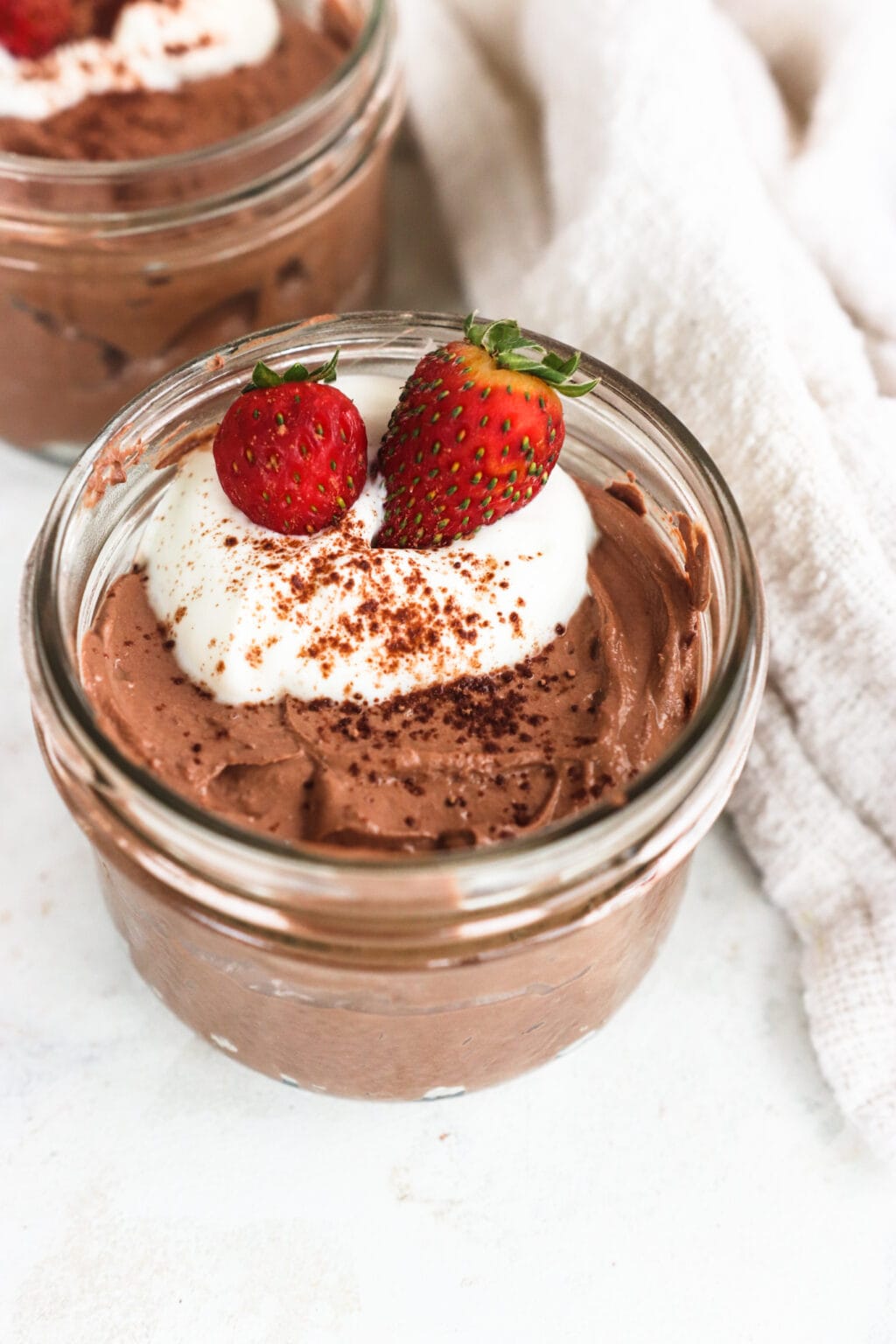 Whipped Greek Yogurt Chocolate Mousse in two glass bowls with whipped cream and strawberries