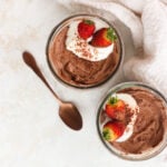 Whipped Greek Yogurt Chocolate Mousse in two glass bowls with whipped cream and strawberries
