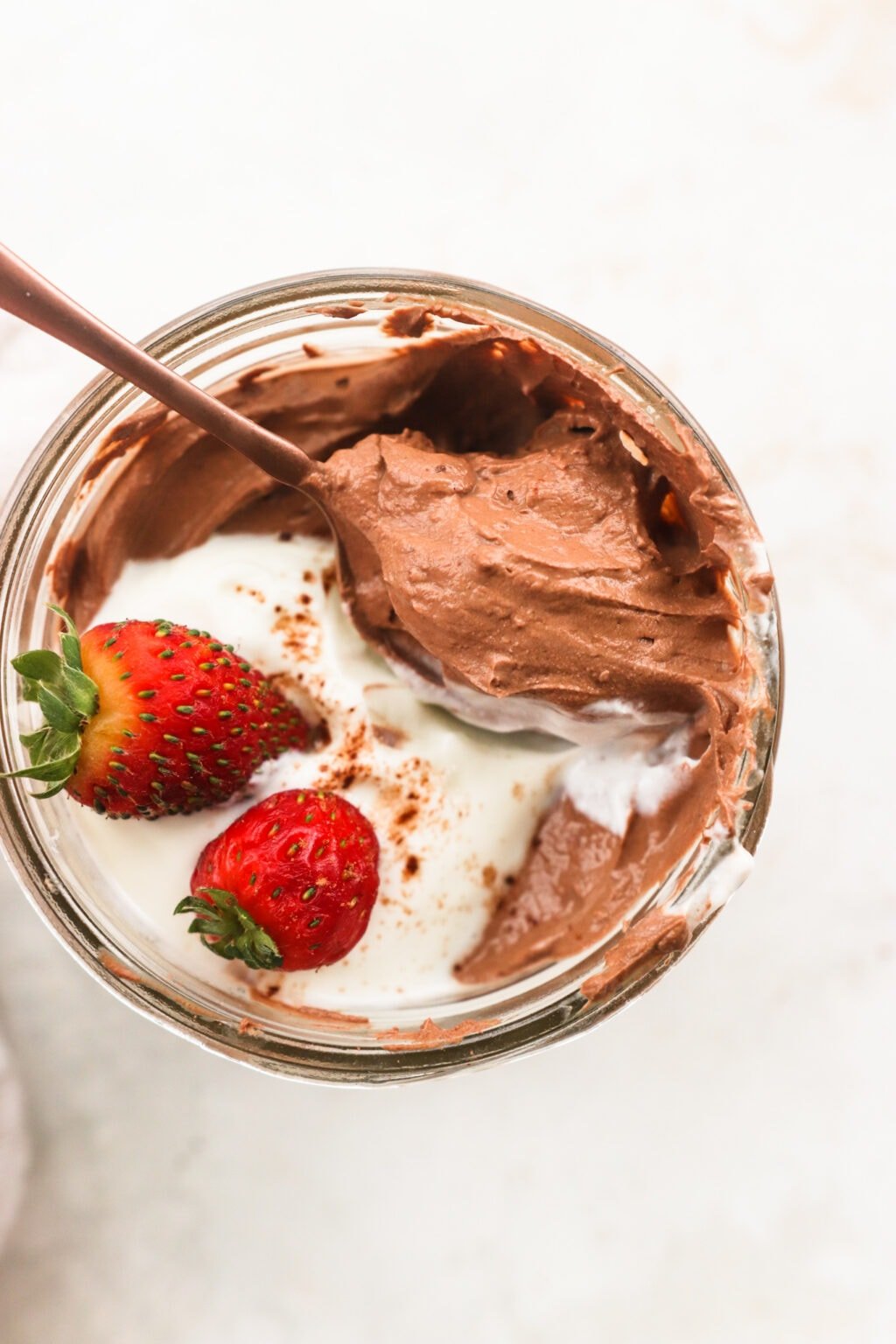 Whipped Greek Yogurt Chocolate Mousse in a glass bowl with whipped cream and strawberries