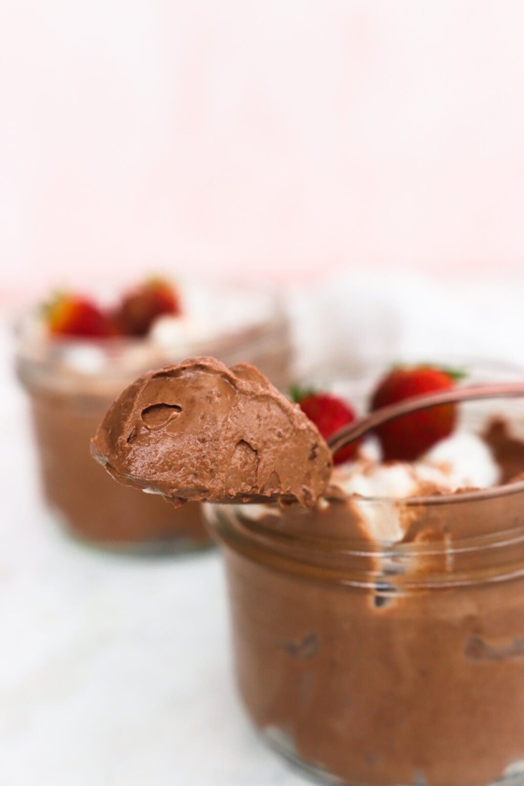 Whipped Greek Yogurt Chocolate Mousse in two glass bowls with whipped cream and strawberries