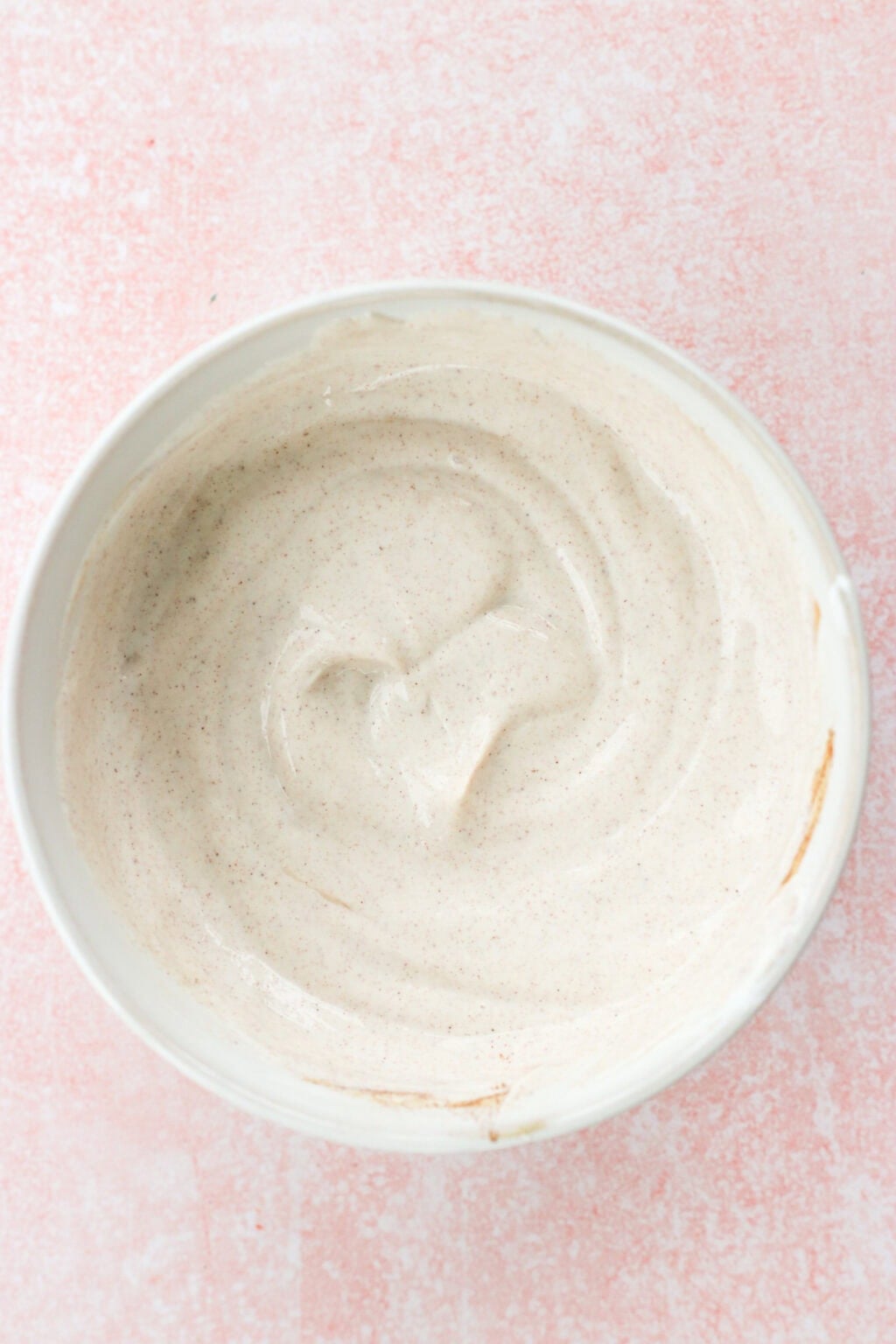 A white bowl of the Best Honey-Cinnamon Greek Yogurt Fruit Dip (easy high protein snack) on a pink countertop
