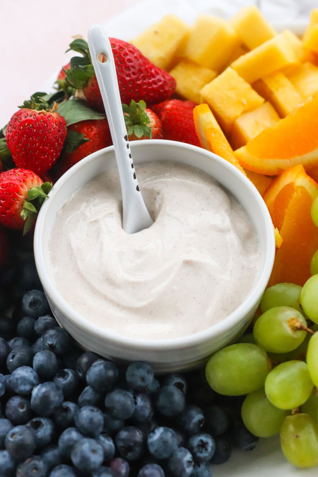 The Best Honey-Cinnamon Greek Yogurt Fruit Dip (easy high protein snack) in a white bowl on top of a tray filled with fruit