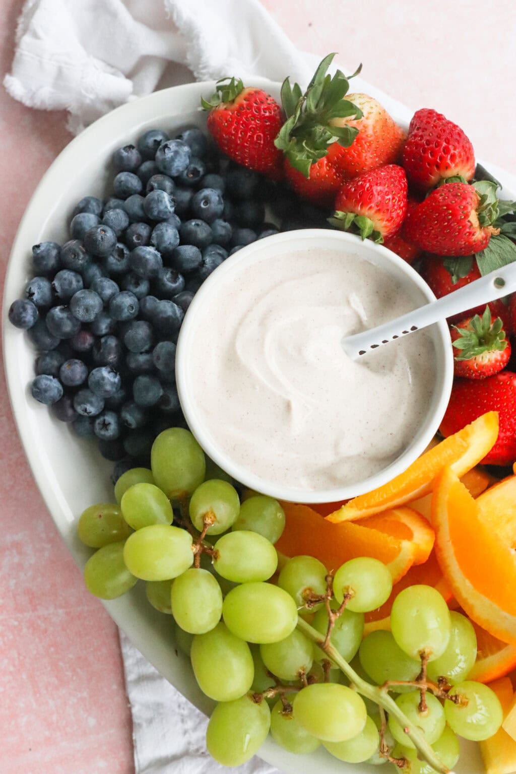 The Best Honey-Cinnamon Greek Yogurt Fruit Dip (easy high protein snack) in a white bowl on top of a tray filled with fruit