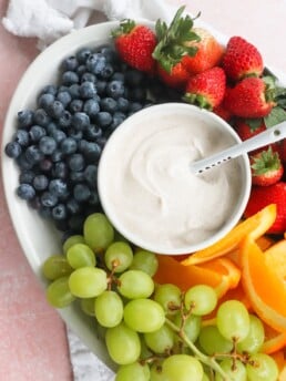 The Best Honey-Cinnamon Greek Yogurt Fruit Dip (easy high protein snack) in a white bowl on top of a tray filled with fruit