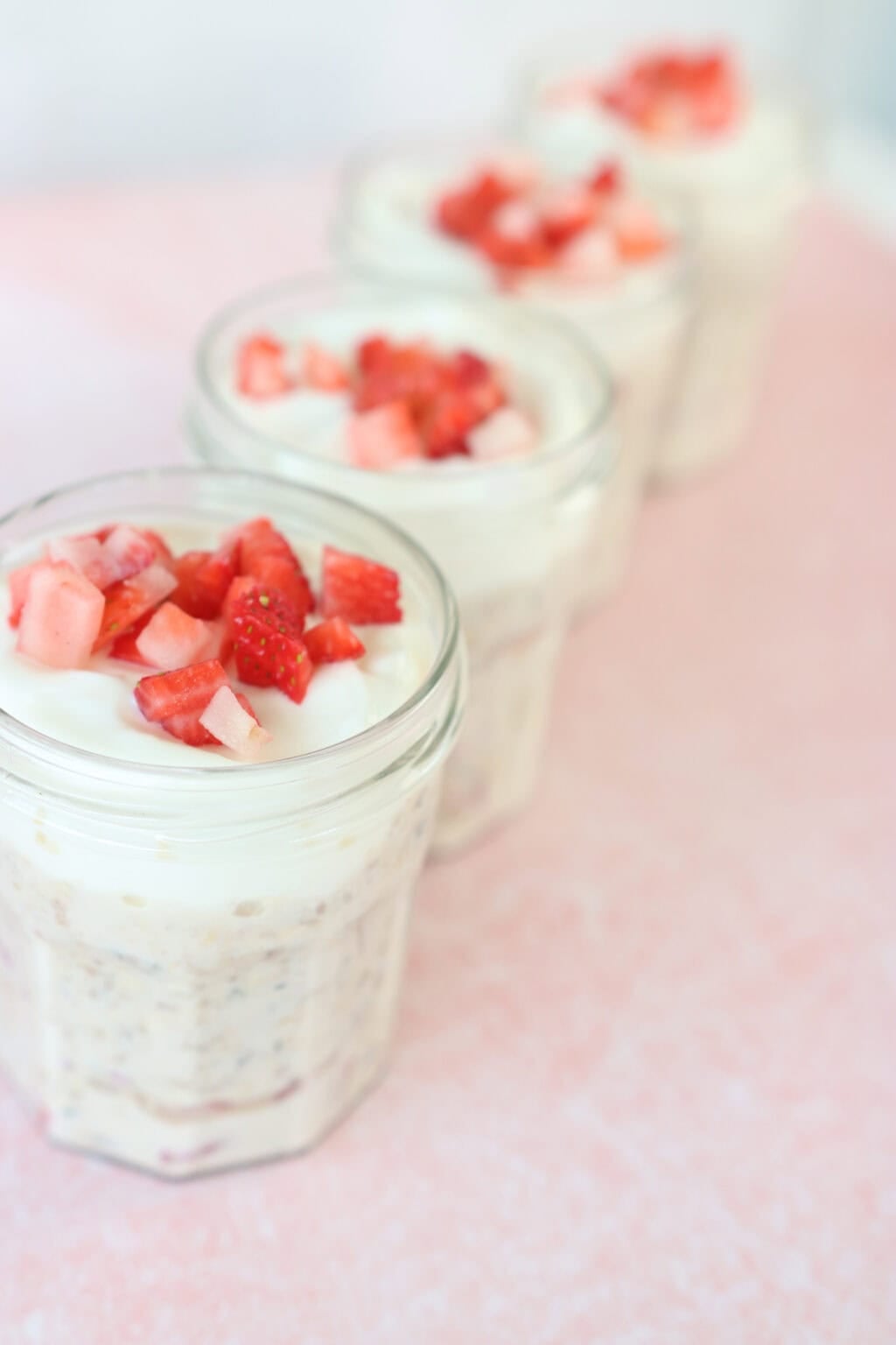 Grab-and-Go Strawberry Overnight Oats in glass jars with strawberries on top