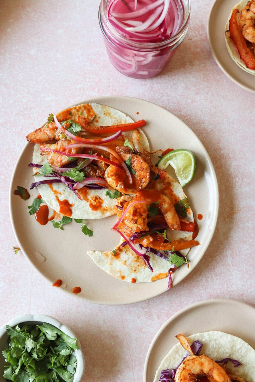 30 Minute Sheetpan Shrimp Fajitas on cream plates with pickled onions on the side
