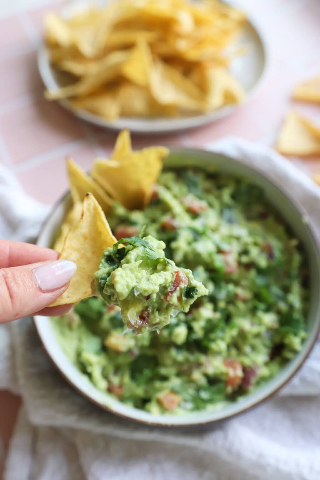 5 Minute Guacamole Dip on a chip with a white bowl in the background