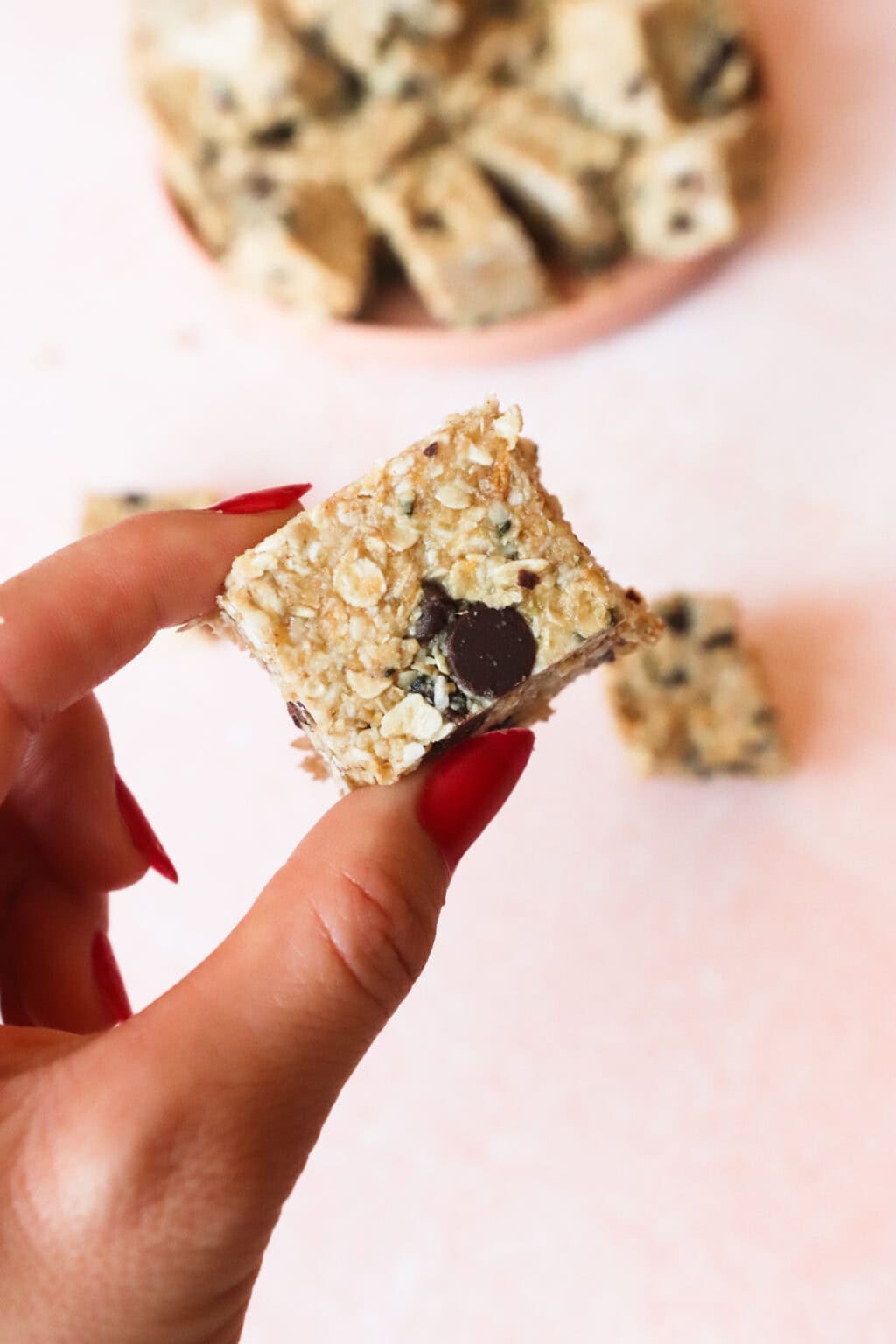 A hand holding one sliced Better Than Store Bought Heavenly Hunk with a pink plate in the background