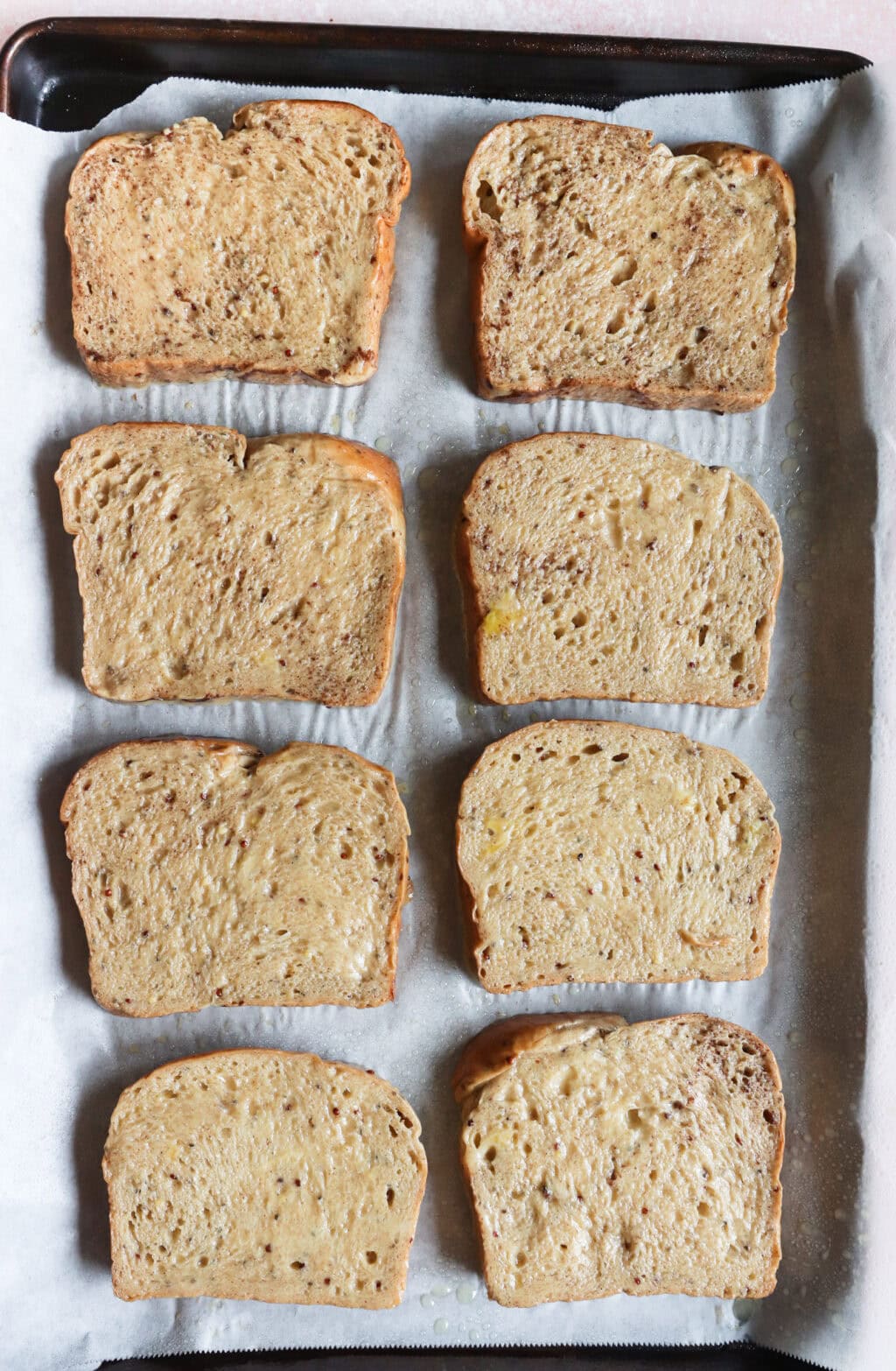 eight slices of toast on a sheet pan ready to be backed for the sheet pan french toast
