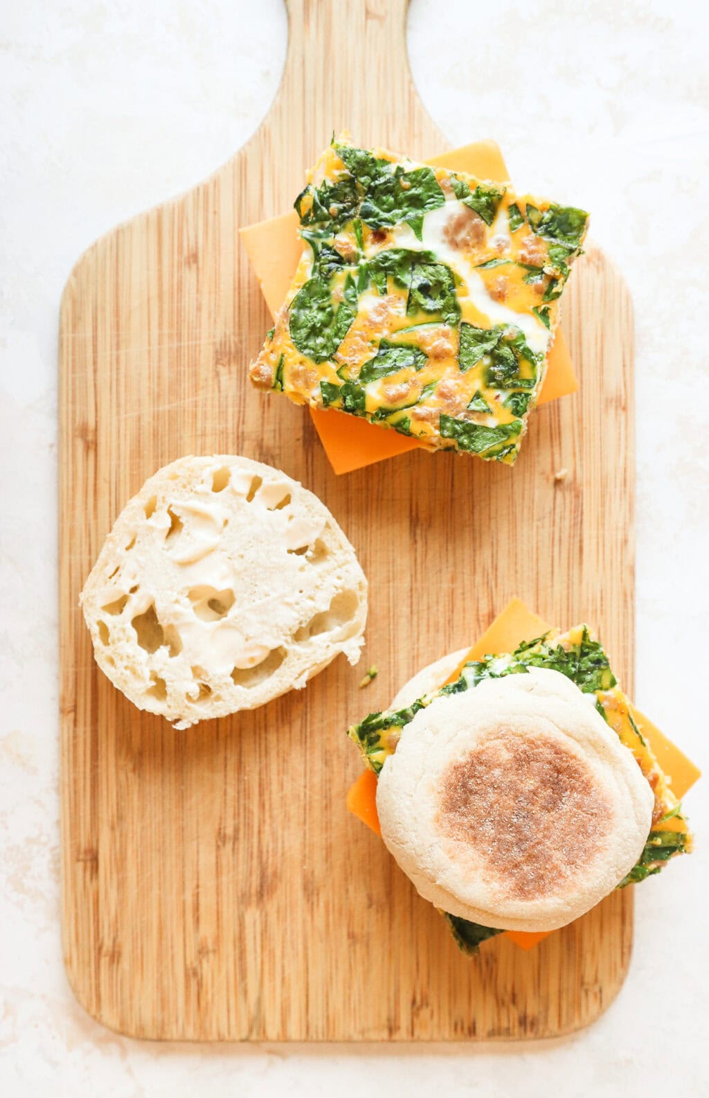 overhead photo of the egg bake breakfast sandwich, one closed sandwich, one open where you can see the egg bake & cheese