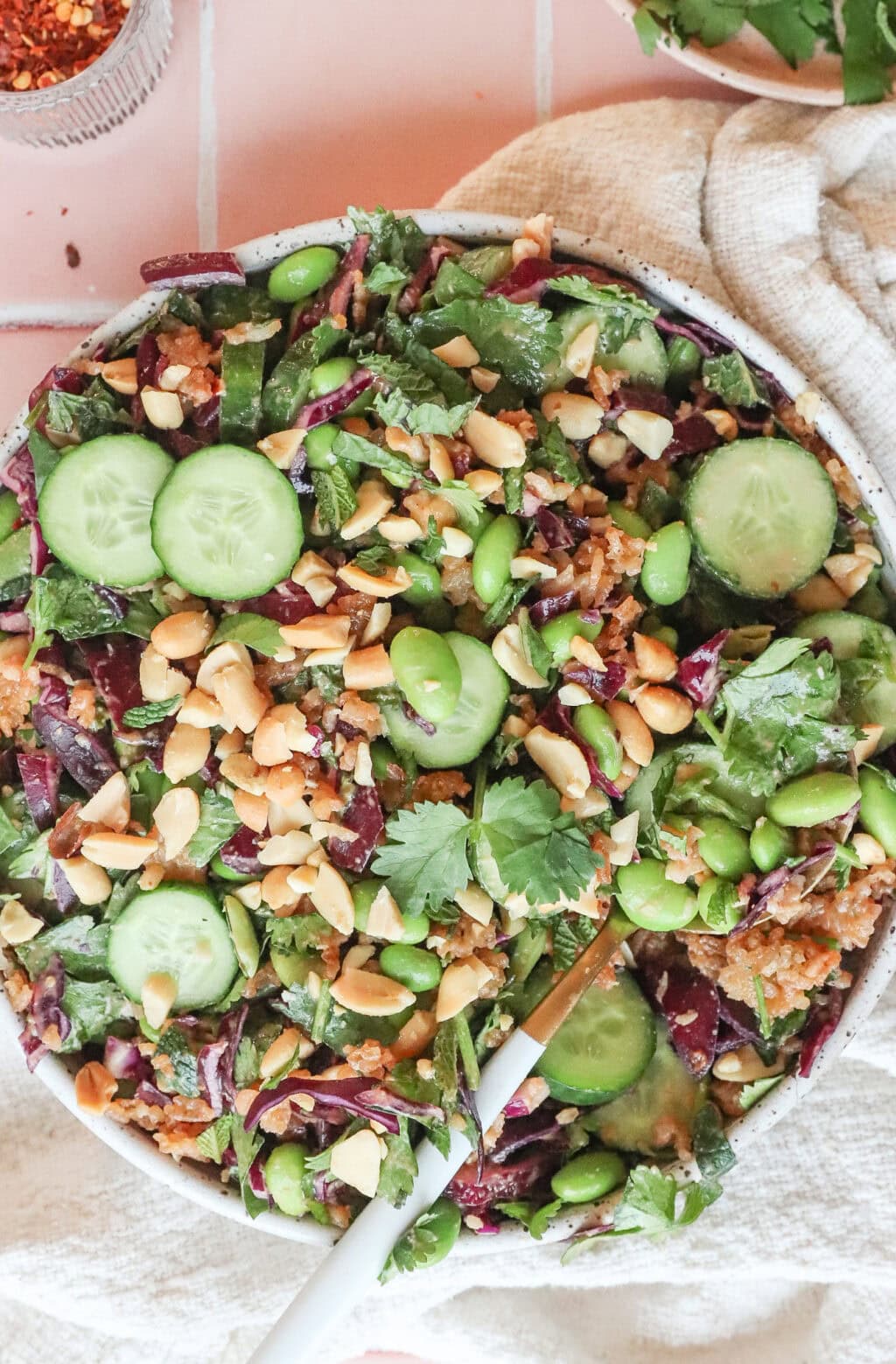 the crispy rice thai salad mixed in a bowl with a gold spoon