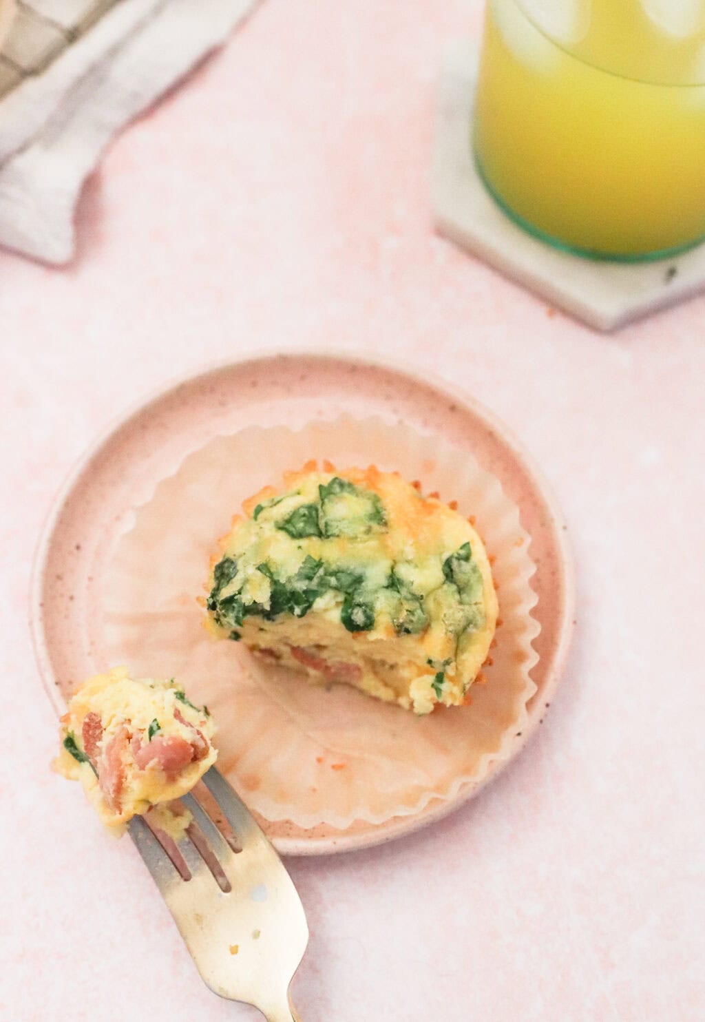 the finished egg bite, cut into with a gold fork, sitting on a pink plate