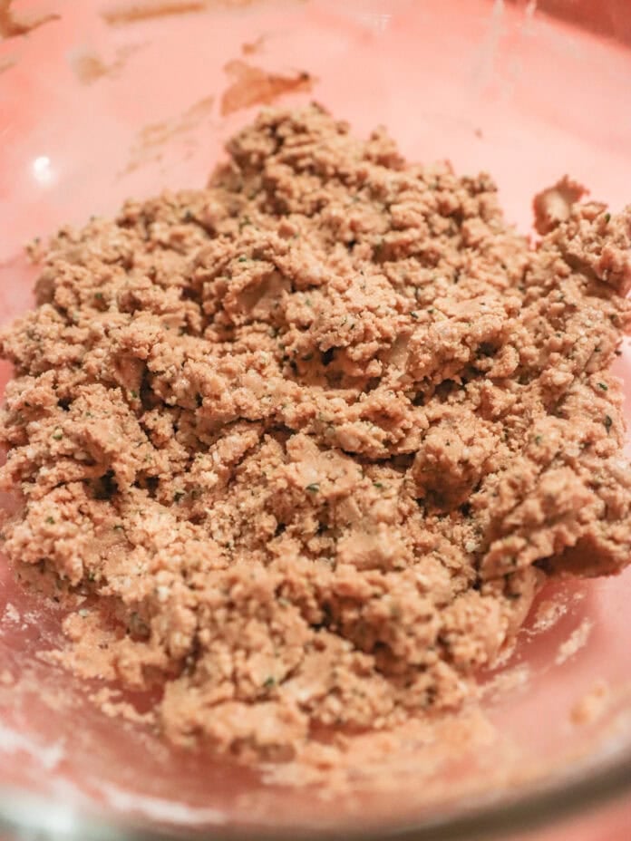 A mixing bowl holds a wet dough-like mixture, with a rcamel brown hue. The bowl is partially visible against a light orange background.