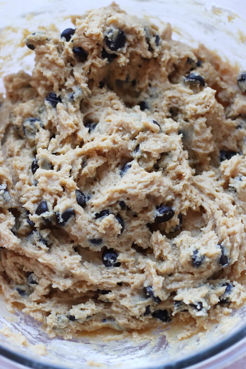 A close-up of a bowl filled with chocolate chip cookie dough, showing a creamy mixture with visible chocolate chips throughout.