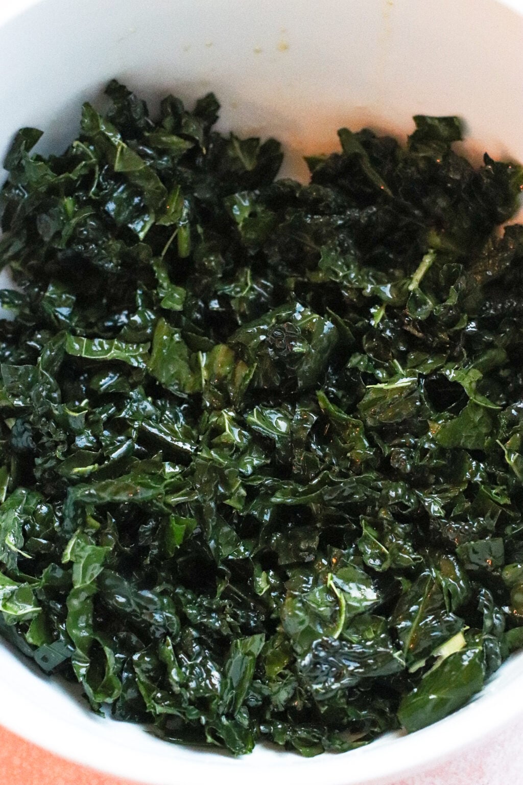 A white bowl filled with chopped, dark green cooked kale.